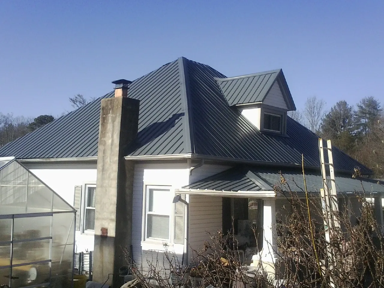 Dark blue standing seam metal roof on a white farmhouse with dormer — Slate & Tile Roof Repair by Roofing Brothers in Lyndora