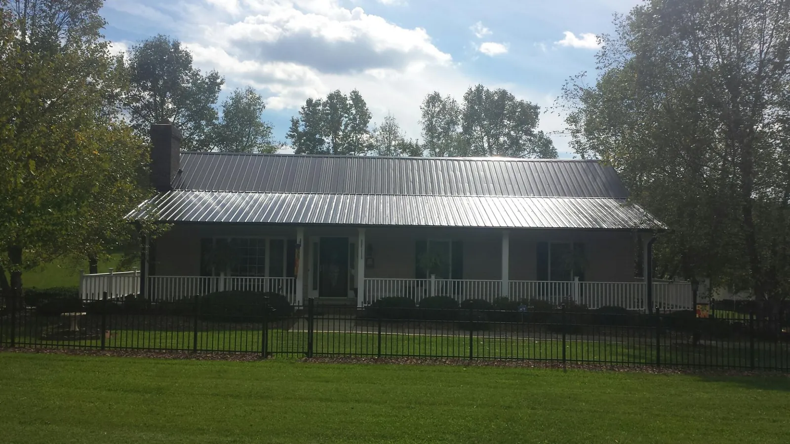 Gray metal roof on a brick ranch with a full width front porch — Gutter Guard Installation work by our crew in Lyndora