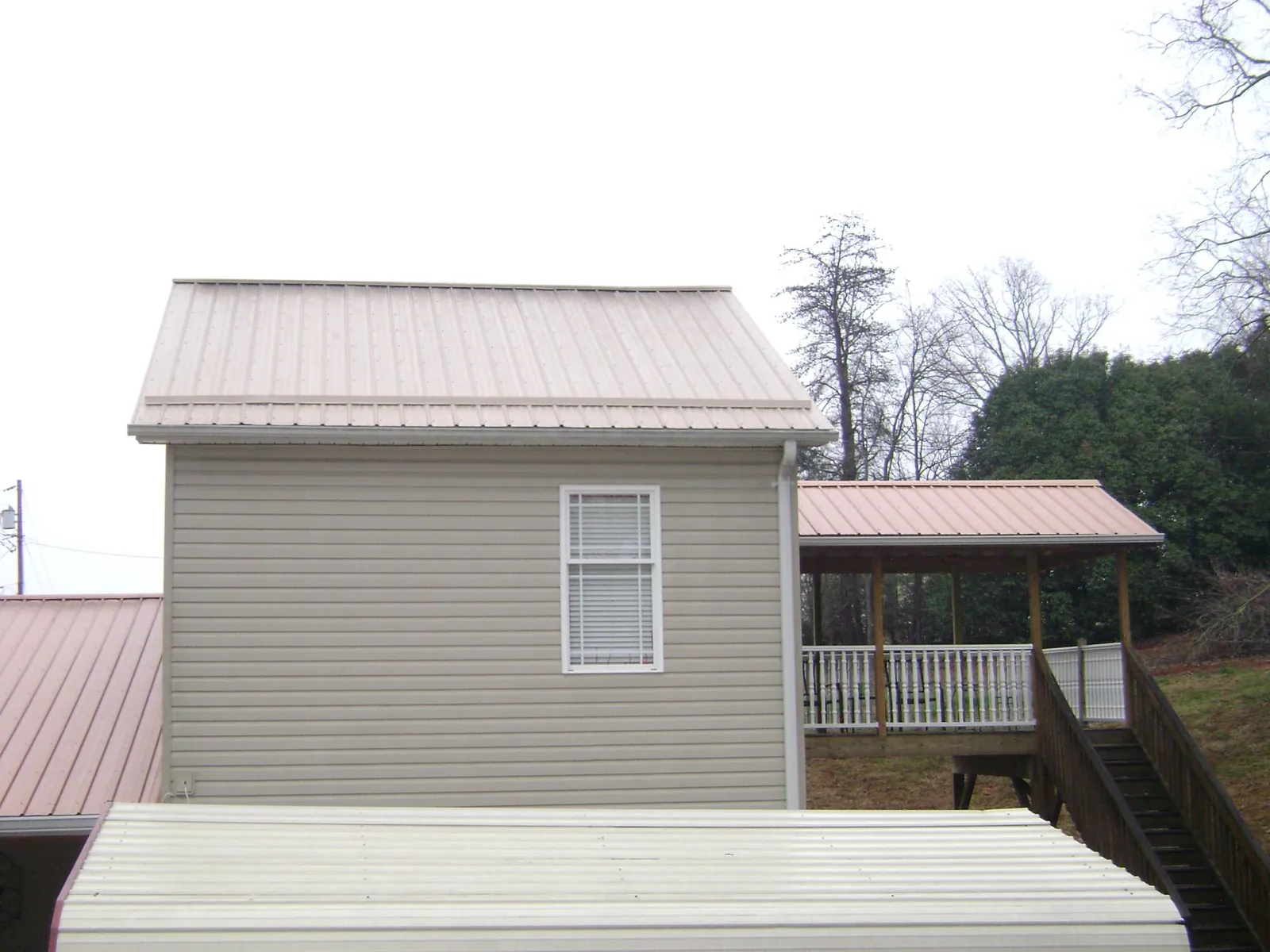 Tan metal roofs on a two story addition and attached porch, from a Roof Replacement job in Lyndora