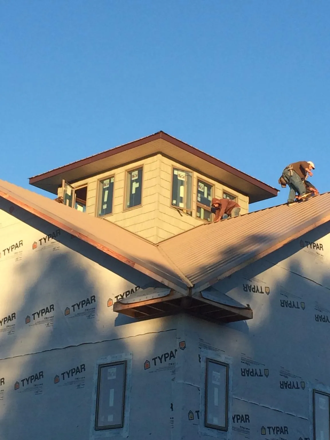 Roofers working around a rooftop cupola on a new metal roof at sunset — Roof Waterproofing in Lyndora by Roofing Brothers